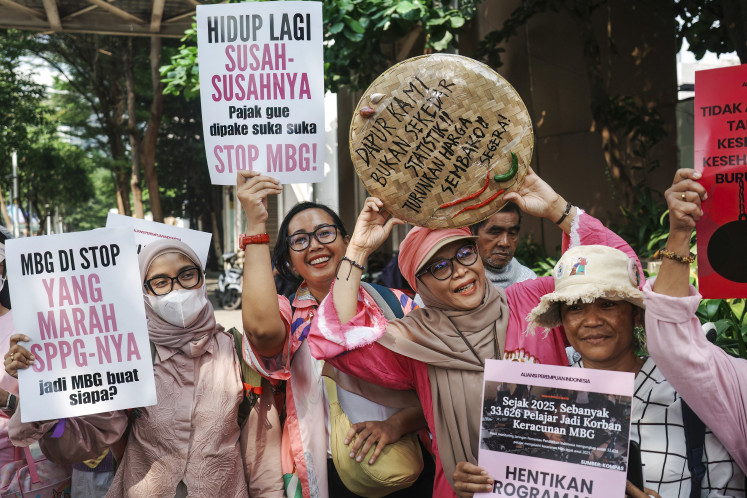 Women carry kitchen utensils and display posters, one of which reads &ldquo;Life is already hard, taxes are used as they please,&ldquo; during a protest demanding the government review the free meal program, lower fuel prices, and open more job opportunities for women, in Jakarta on June 18, 2026. (Photo by BAY ISMOYO / AFP)