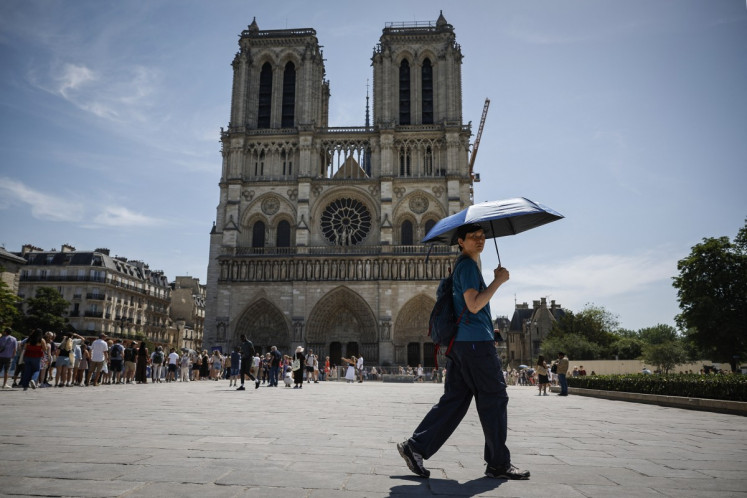 A tourist shelters from the sun under an umbrella in front of Notre-Dame Cathedral in Paris, France as a record-breaking early heatwave scorches a swathe of western Europe on May 28, 2026. The heatwave that is expected to hit France from June 17 could send temperatures soaring to &ldquo;peaks of 40 degrees Celsius&ldquo; on June 21, coinciding with the summer solstice, M&eacute;t&eacute;o-France has warned.