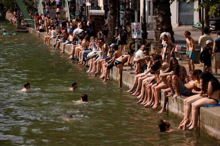 People enjoy the sun along the Canal Saint-Martin as public swimming has been allowed earlier on part of it due to rising temperatures, in Paris as a heatwave hits a large area of France, June 18, 2026.
