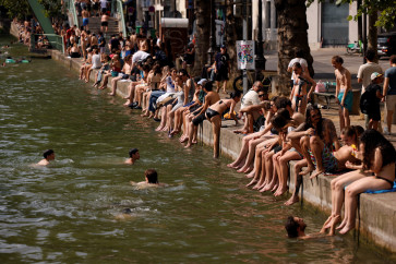 People enjoy the sun along the Canal Saint-Martin as public swimming has been allowed earlier on part of it due to rising temperatures, in Paris as a heatwave hits a large area of France, June 18, 2026.