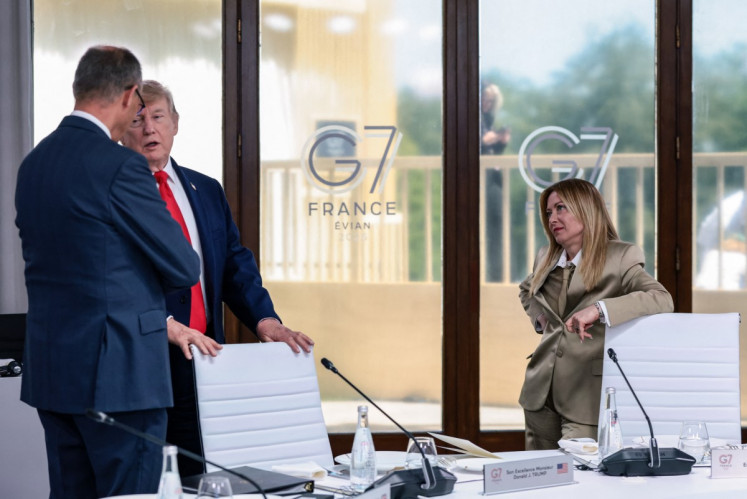 US President Donald Trump speaks with Germany's Chancellor Friedrich Merz next to Italy's Prime Minister Giorgia Meloni during a work lunch as part of the G7 summit, in Evian, eastern France, on June 16, 2026. 