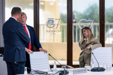 US President Donald Trump speaks with Germany's Chancellor Friedrich Merz next to Italy's Prime Minister Giorgia Meloni during a work lunch as part of the G7 summit, in Evian, eastern France, on June 16, 2026. 