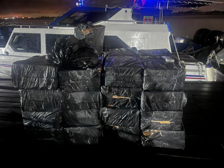 Boxes of illicit cigarettes are stacked in front of a customs patrol boat in an undisclosed location in Batam city, Riau Islands, in this undated picture released by Batam Customs and Excise Office. 11 out of 54 interdictions made in May consisted of cigarettes.  