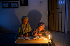 Night study: Two children recite the Quran on June 19, 2026 by candlelight during a scheduled power outage in Cinunuk in West Java. PLN West Java Distribution Main Unit (UID Jawa Barat) implemented limited load management through rolling blackouts in several areas of Greater Bandung due to technical operational issues at power plants and disruptions affecting two major generating units. 
