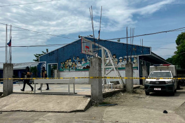 Police investigators walk in front of the school entrance after a shooting incident at a high school compound in Tacloban City, Leyte province on June 22, 2026. At least three teenaged students were killed and five others wounded on June 22, in a rare school shooting in the central Philippines, police said. 