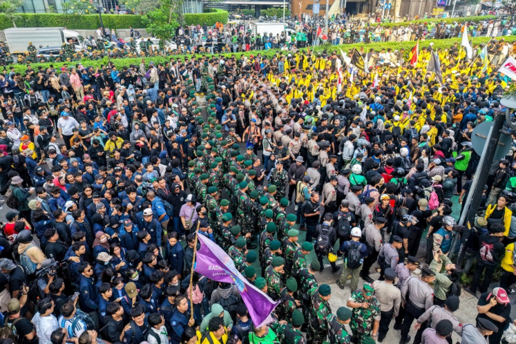 Indonesian Military (TNI) personnel (center) stand guard behind police personnel to block the path of students protesting demanding a reduction in fuel prices and the dissolution of President Prabowo Subianto's free nutritious meal program, which they consider to be a hotbed of corruption, on June 12 in Jakarta. 