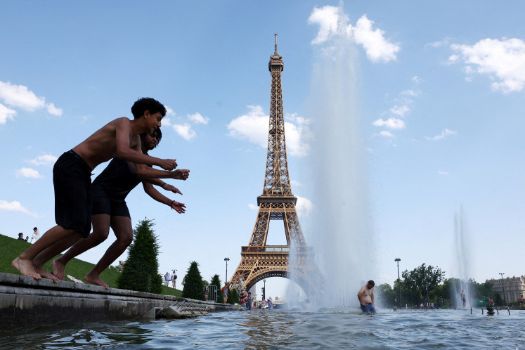 People cool off in the Trocadero Fountain next to the Eiffel Tower in Paris as temperatures rise during a heatwave affecting a large part of France, June 22, 2026.