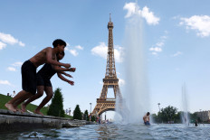 People cool off in the Trocadero Fountain next to the Eiffel Tower in Paris as temperatures rise during a heatwave affecting a large part of France, June 22, 2026.
