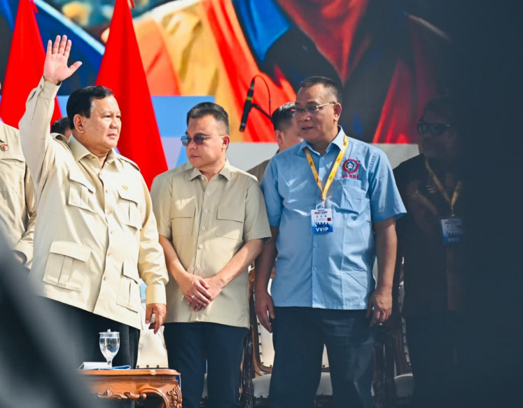 President Prabowo Subianto (left) raises his hand alongside Deputy House Speaker Sufmi Dasco Ahmad (center) during a May Day rally on May 1 attended by thousands of workers at the National Monument (Monas) square in Central Jakarta.