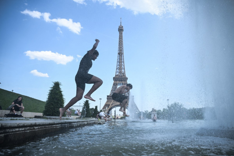 People jump in the Trocadero Fountain near the Eiffel Tower during a heatwave in Paris on June 22, 2026. 