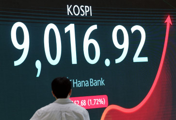 A currency dealer walks past an electronic board displaying the Korea Composite Stock Price Index (KOSPI), at the dealing room of a bank in Seoul, South Korea, June 18, 2026.