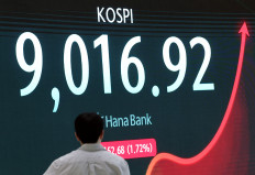 A currency dealer walks past an electronic board displaying the Korea Composite Stock Price Index (KOSPI), at the dealing room of a bank in Seoul, South Korea, June 18, 2026.
