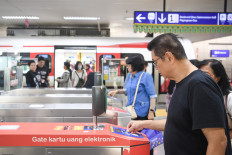 Tap and go: Passengers tap electronic fare cards after disembarking from an LRT train on June 22 at Velodrome Station in East Jakarta.