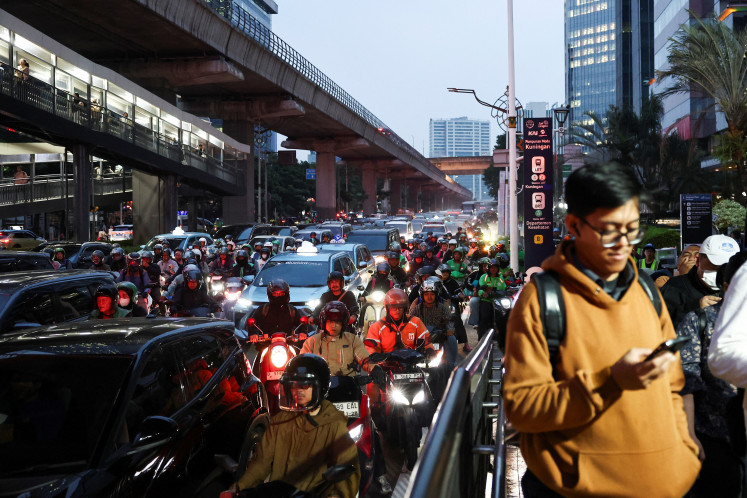 Afternoon gridlock: Motorcyclists weave through traffic as commuters queue to enter an LRT station during the afternoon rush hour in Jakarta on June 10, 2026.