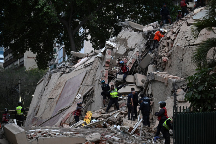 Rescuers search for victims in a collapsed building following an earthquake in Caracas on June 24, 2026. Two earthquakes of magnitude 7.2 and 7.5 struck the same area of Venezuela on the evening of June 24, causing buildings to collapse, according to the United States Geological Survey (USGS) and AFP journalists. The quakes drove residents of the capital, Caracas, into the streets.
