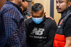 Police escort suspect Taufik Hidayat (center) at the West Java Police headquarters in Bandung on June 23 after his arrest in Majalaya, Bandung regency. He is accused of confining and severely abusing a woman identified as YTR for three years. 