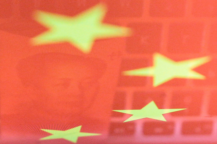 A China yuan banknote featuring late Chinese chairman Mao Zedong and a computer keyboard are seen reflected on an image of Chinese flag in this illustration picture taken on Nov. 1, 2019.