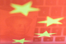 A China yuan banknote featuring late Chinese chairman Mao Zedong and a computer keyboard are seen reflected on an image of Chinese flag in this illustration picture taken on Nov. 1, 2019.