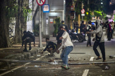 A student throws a rock at riot police during protest against a rise in non-subsidized fuel prices, inefficient government spending and military involvement in civilian affairs and the government's free school meals program in Surabaya, East Java on June 26, 2026. 