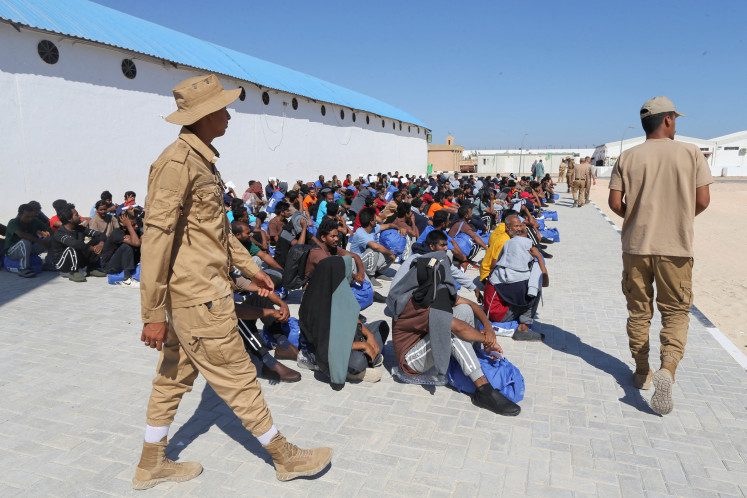 Bangladeshi migrants sit on June 24, 2026, on the ground inside the illegal immigration department headquarters in Benghazi, Libya, amid deportation to their country of origin.