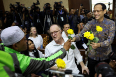 A supporter gives a rose to Nadiem Makarim, former education minister and co-founder of ride-hailing firm Gojek, who is accused by prosecutors of using his executive powers to enrich himself, as Nadiem arrives at the courtroom for the verdict in a corruption case, related to the procurement of Google Chromebook laptops, at the Central Jakarta Court in Jakarta on June 30, 2026.