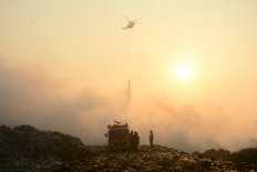 A water-bombing helicopter drops water on a fire on Wednesday at the Jatiwaringin landfill in Tangerang Regency, Banten. On the second day of firefighting efforts, the National Disaster Mitigation Agency (BNPB) deployed two water-bombing helicopters to help contain the blaze, which had spread across about 15 hectares of the landfill's 33-ha site. Authorities said the fire was caused by a combination of extreme heat and methane gas generated by decomposing waste.