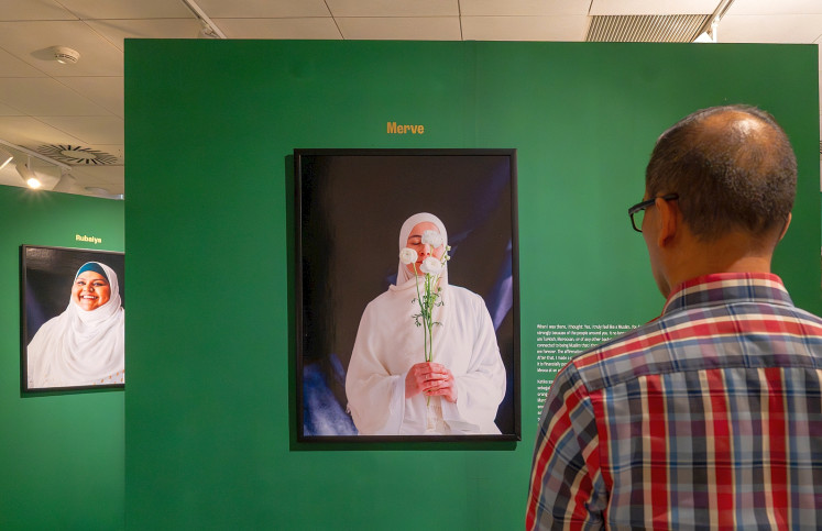 Private faith: A visitor contemplates a portrait of a Dutch Muslim woman concealing her face with a bunch of flowers on May 19, 2026, during the opening of Labbayk: Here I Am, a photo exhibition by Turkish-Dutch sociologist and photographer Ebru Aydin at Erasmus Huis in Setiabudi, South Jakarta.