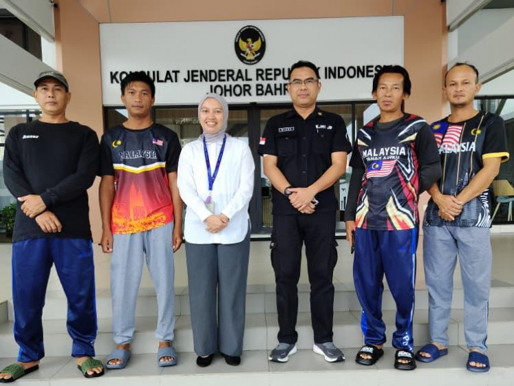 Two diplomats from the Indonesian Consulate General in Johor Bahru (third left and third right) are flanked by four fishermen from Bintan regency, Riau Islands, prior to the fishermen's repatriation on July 2, 2026, at the consulate general in Johor Bahru, Malaysia. The fishermen were cleared of criminal charges of trespassing into Malaysian waters without proper documents.