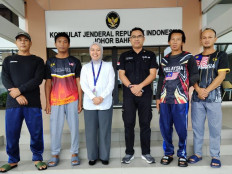 Two diplomats from the Indonesian Consulate General in Johor Bahru (third left and third right) are flanked by four fishermen from Bintan regency, Riau Islands, prior to the fishermen's repatriation on July 2, 2026, at the consulate general in Johor Bahru, Malaysia. The fishermen were cleared of criminal charges of trespassing into Malaysian waters without proper documents.