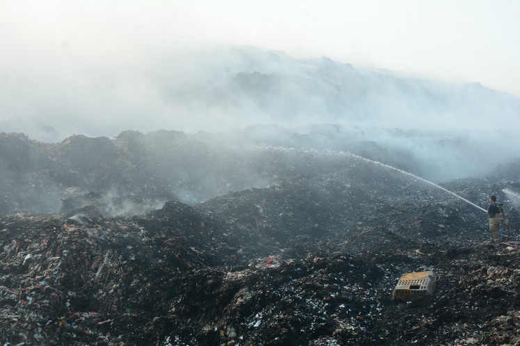 A firefighter battles a blaze at the Jatiwaringin landfill in Tangerang regency, Banten, on July 4, 2026.