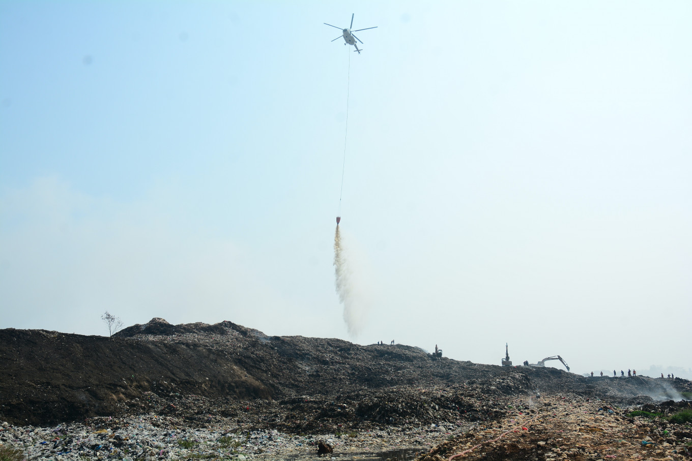 A water-bombing helicopter operated by Indonesia's National Disaster Mitigation Agency (BNPB) drops water on a landfill fire  on July 4 at the Jatiwaringin landfill in Tangerang Regency, Banten, Indonesia.
