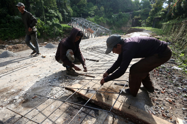 Residents repair the Bireuen-Central Aceh national highway in the Tajuk Enang-Enang area of Pintu Rime Gayo district, Bener Meriah regency, Aceh, on June 12, 2026. Community members raised funds and contributed labor to repair the heavily damaged highway and a bridge whose structure collapsed and was buried by debris following severe flooding in late November 2025.