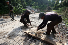 Residents repair the Bireuen-Central Aceh national highway in the Tajuk Enang-Enang area of Pintu Rime Gayo district, Bener Meriah regency, Aceh, on June 12, 2026. Community members raised funds and contributed labor to repair the heavily damaged highway and a bridge whose structure collapsed and was buried by debris following severe flooding in late November 2025.