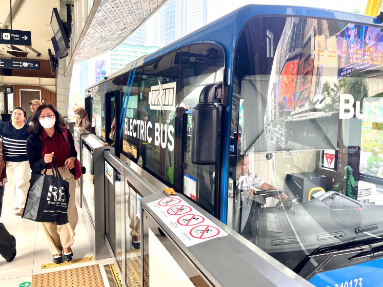 Passengers walk after disembarking from a TransJakarta bus on July 7, 2026, at the Hotel Indonesia traffic circle bus stop in Central Jakarta, Indonesia.