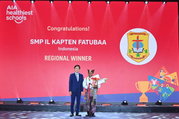 Teacher and project lead at the SMP Il Kapten Fatubaa junior high school in Belu regency, East Nusa Tenggara, Antonius Kapitan (right) receives the grand prize in the AIA Healthiest Schools Competition from AIA Group chief executive and president Lee Yuan Siong during a ceremony in Bangkok on Wednesday. 