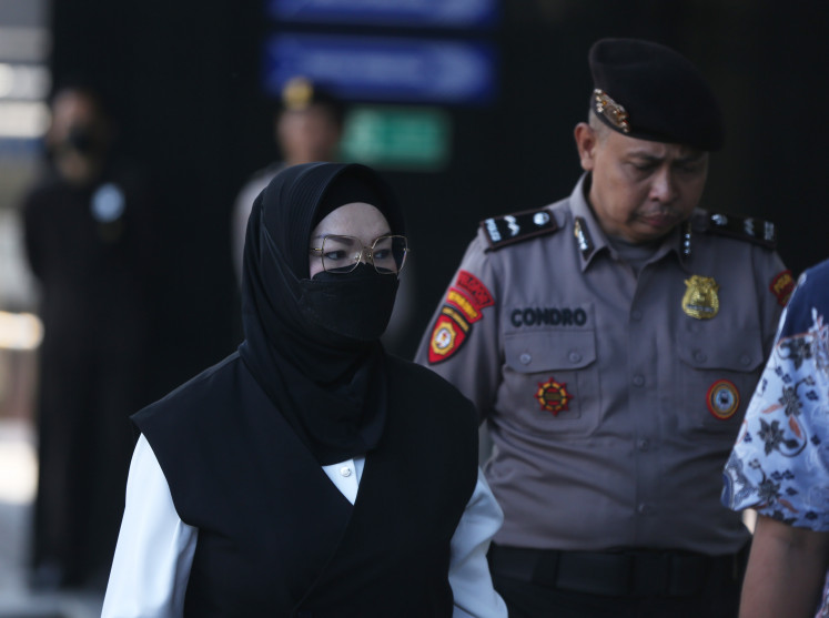 Sukoharjo Regent Etik Suryani (left) is escorted by police officers on Friday upon her arrival for questioning at the Corruption Eradication Commission (KPK) Headquarters in Jakarta. Etik was apprehended along with seventeen others in a graft raid over alleged extortion targeting officials in the Sukoharjo administration.