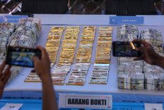 Journalists photograph gold and cash displayed as evidence during a news conference on July 10 at the Jakarta Police headquarters. Police said investigators are continuing to examine evidence collected during searches at 13 locations as part of a joint investigation into three alleged cases involving corruption, bribery, gratuities and money laundering. 