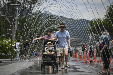 People walk through a fountain tunnel to cool off at Gwanghwamun Square in Seoul on July 12, 2026.