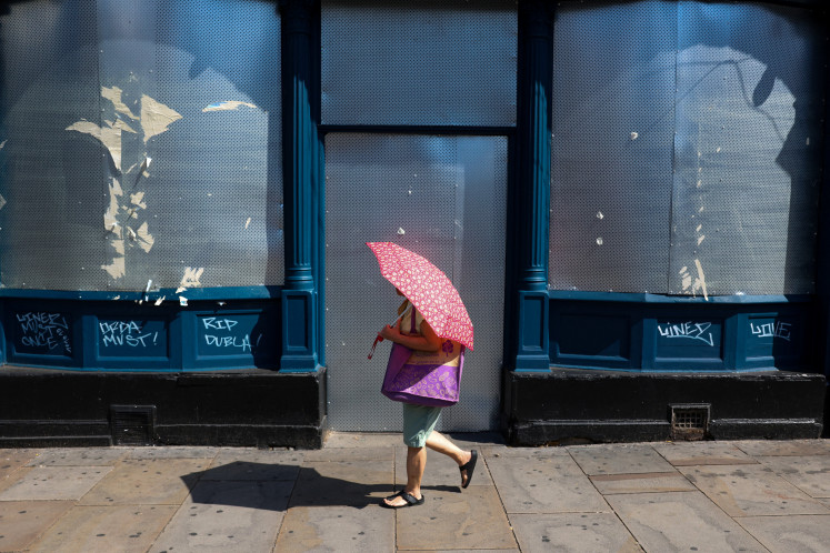 A woman walks with an umbrella to shelter from the sun as Britain experiences record temperatures during a heatwave in Fulham, London, Britain, June 26, 2026.