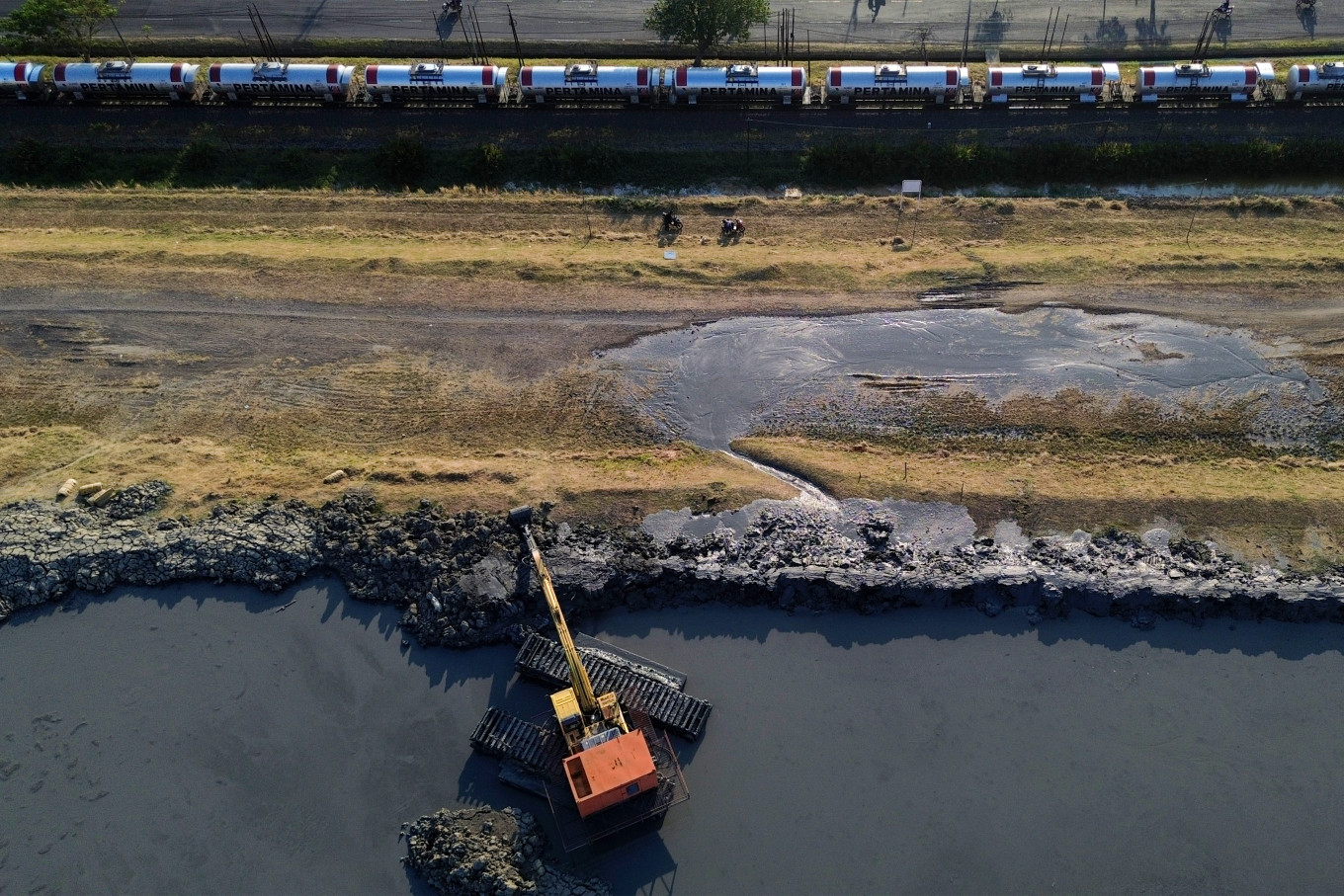 An aerial view shows heavy equipment reinforcing and raising the Lapindo mudflow embankment in Siring subdistrict, Porong district, Sidoarjo regency, East Java, on July 10, 2026. The work is intended to strengthen the embankment after a leak developed due to land subsidence and increased pressure from mud in the containment pond.