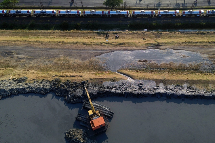 An aerial view shows heavy equipment reinforcing and raising the Lapindo mudflow embankment in Siring subdistrict, Porong district, Sidoarjo regency, East Java, on July 10, 2026. The work is intended to strengthen the embankment after a leak developed due to land subsidence and increased pressure from mud in the containment pond.