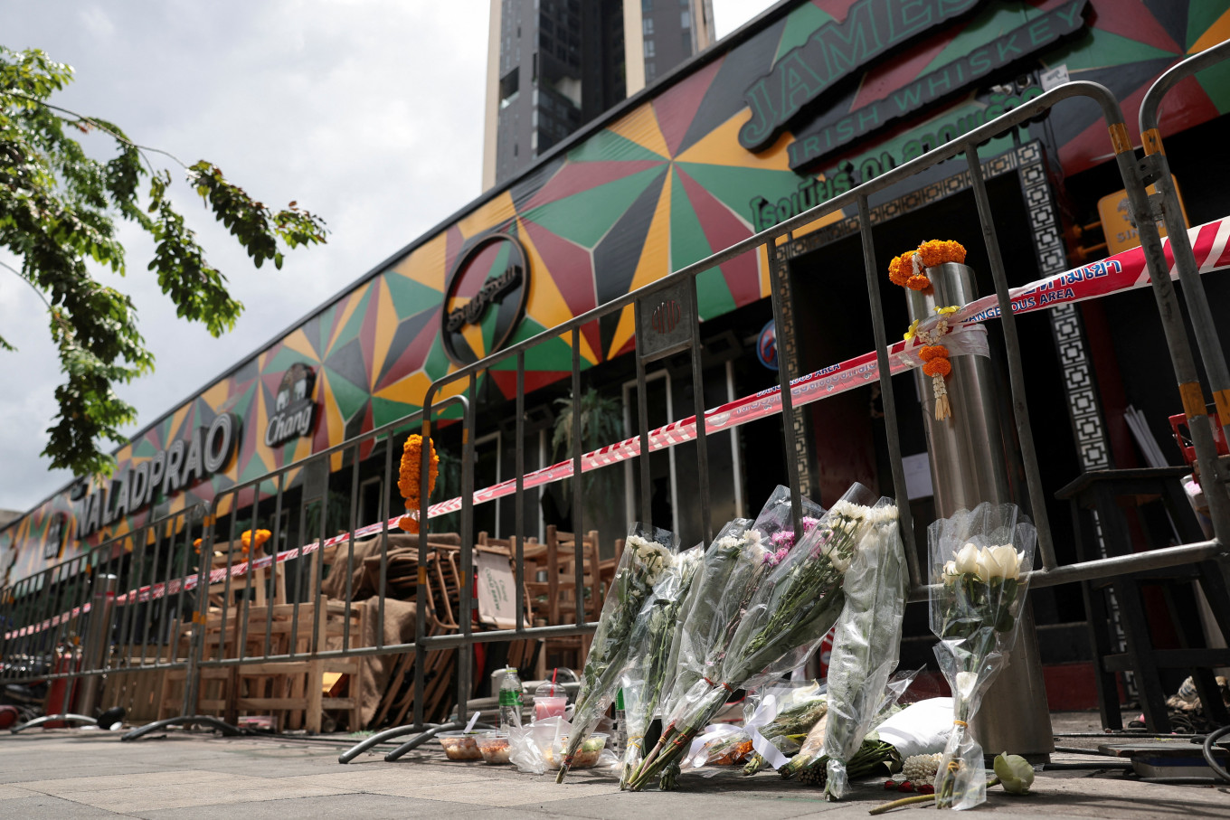 Flowers and offerings are placed outside Rong Beer Na Lat Phrao bar, the site of a deadly fire, to pay tribute to victims who lost their lives in the bar fire, the day after the incident, in Bangkok, Thailand, July 14, 2026.
