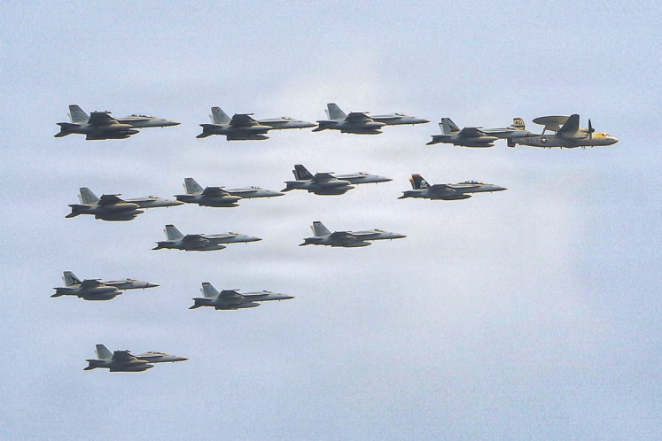 This US Navy handout photo released on July 15, 2026 and taken on June 30 by US Central Command Public Affairs shows fixed wing aircraft flying over Arleigh Burke-class guided-missile destroyer USS Frank E. Petersen Jr. during a photo exercise. The US launched a wave of strikes against Iran on July 15, after it reimposed a naval blockade in a return to war between the two foes.