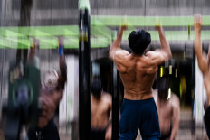 Strength in balance: Men do pull-ups on Nov. 5, 2025, at Bercy Street Workout, an outdoor fitness park in Paris.