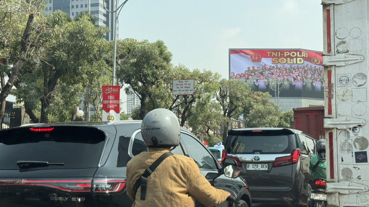 A motorcyclist weaves through Jakarta traffic on Thursday, July 16, 2026 in clear view of an imposing sign that depicts the National Police and the Indonesian Military (TNI) closing ranks. The signage emerged in the aftermath of a heated rivalry in early July between the police and the Attorney General's Office (AGO) that also involved the TNI, which led to the resignation of top prosecutor Febrie Adriansyah.
