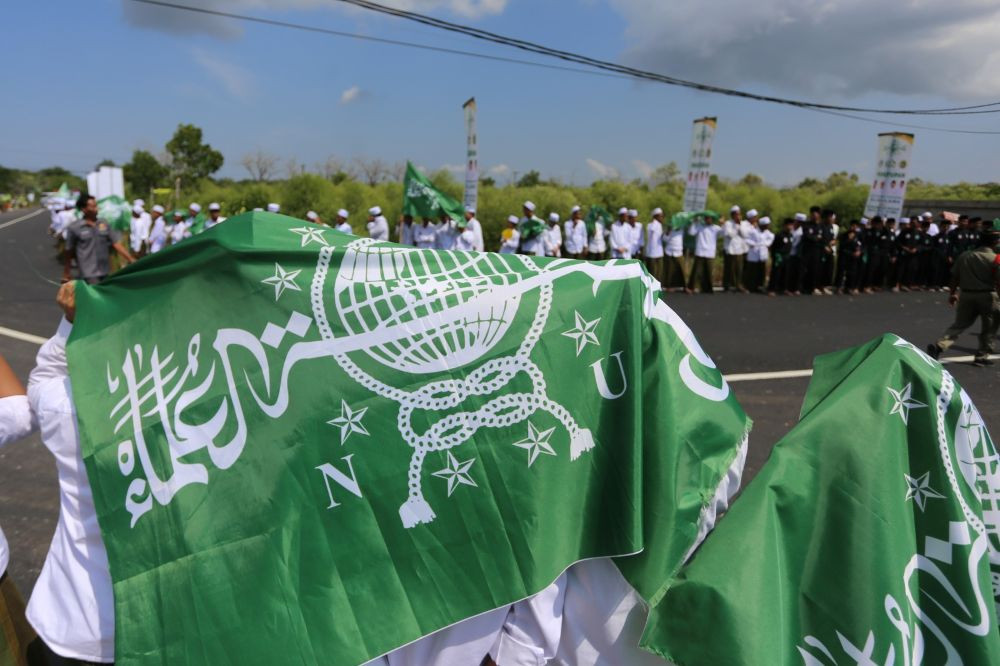 Bated breath: Groups of santri (Islamic boarding school students) hold aloft the flag of Muslim organization Nahdlatul Ulama (NU) as they wait along a road for the presidential motorcade to arrive on June 23, 2026, ahead of the closing ceremony of the NU National Conference of Islamic Scholars and Grand Conference at the Syachona Mohammad Cholil Islamic Institute in Bangkalan, East Java.