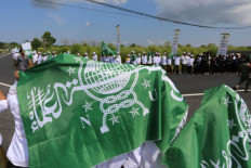 Bated breath: Groups of santri (Islamic boarding school students) hold aloft the flag of Muslim organization Nahdlatul Ulama (NU) as they wait along a road for the presidential motorcade to arrive on June 23, 2026, ahead of the closing ceremony of the NU National Conference of Islamic Scholars and Grand Conference at the Syachona Mohammad Cholil Islamic Institute in Bangkalan, East Java.