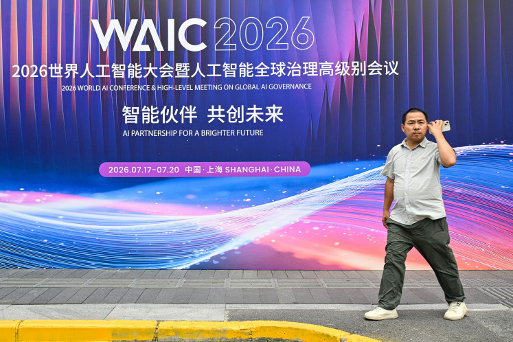 A man walks past signage for the World Artificial Intelligence Conference (WAIC) in Shanghai on July 16, 2026.
