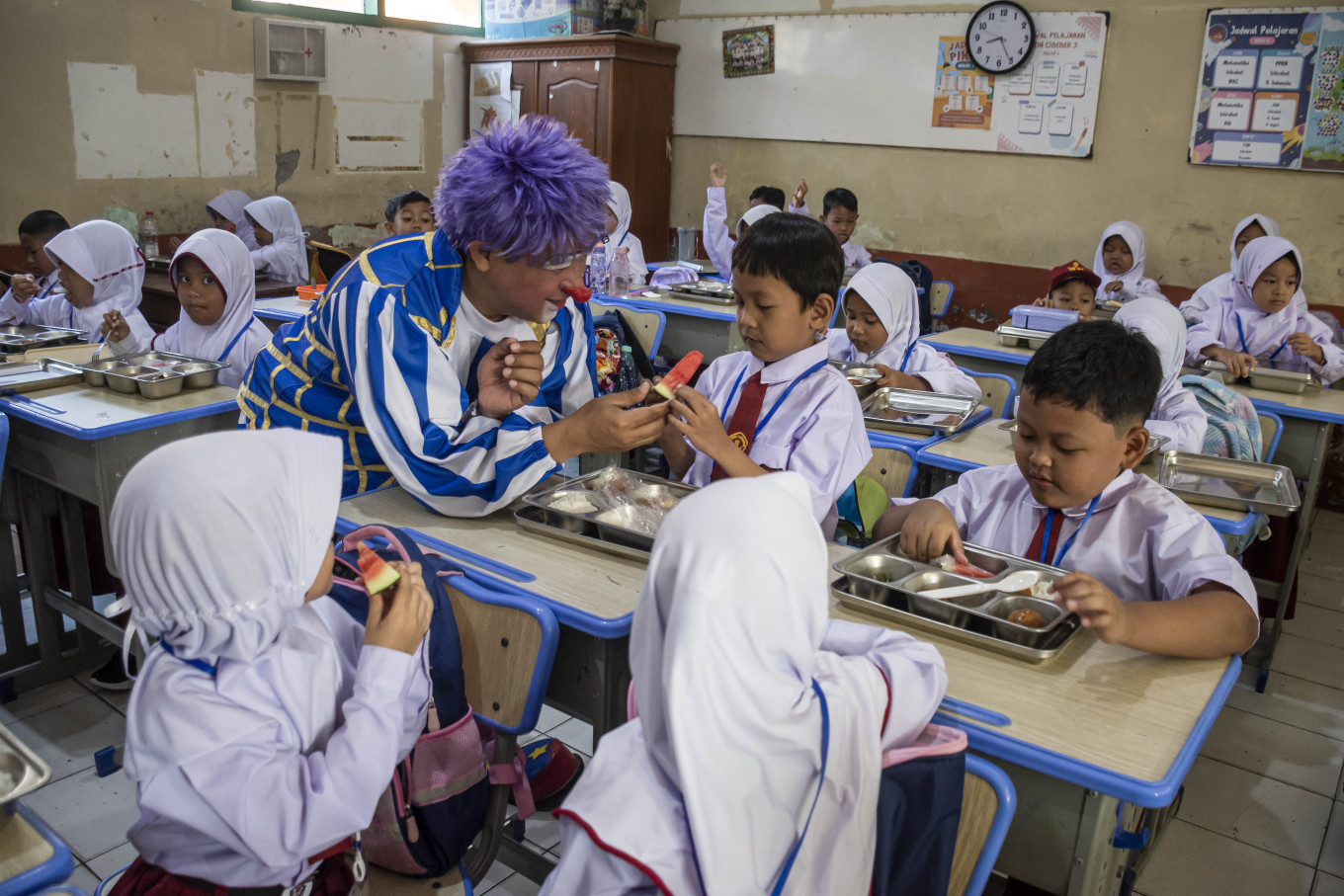 Members of the Cimahi Clown Community distribute free meals to new students during the school orientation program at the SDN Cibeber elementary school complex in Cimahi, West Java, on July 14, 2026. The community organized entertainment, motivational activities and educational sessions on the &ldquo;Seven Habits of Great Indonesian Children&ldquo; while promoting the government's free meals program to help new students feel safe and welcome. 