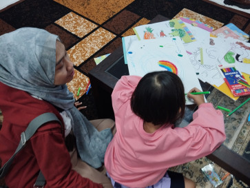 Life after divorce: Rizkynia Nabila (left) accompanies her daughter as she draws on June 20, 2026, in Jakarta. Nabila is among several single mothers who say court-ordered child support has been paid inconsistently following their divorce.